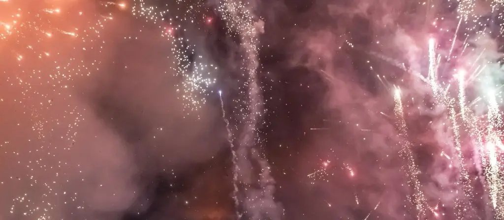 Pink, gold and white fireworks bursting against a dark sky