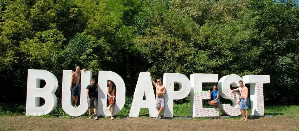 Festival-goers posing on and around the giant white BUDAPEST letters at the Sziget festival entrance