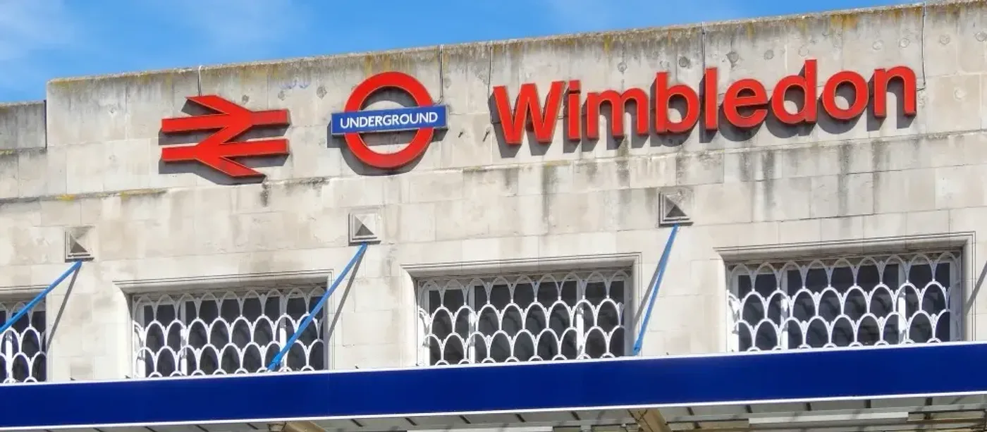 Wimbledon station exterior showing the British Rail and London Underground roundel logos on a white art deco building facade against a blue sky